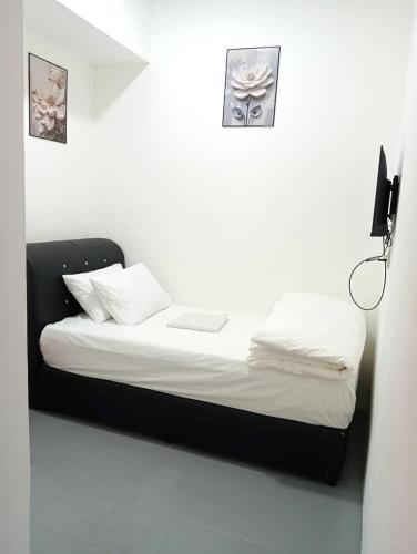 a bed in a white room with a laptop on it at H Budget Hotel in Johor Bahru