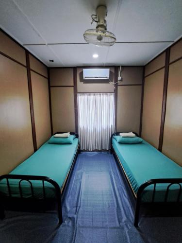 a small room with two beds and a window at Benteng Taman Negara in Jerantut