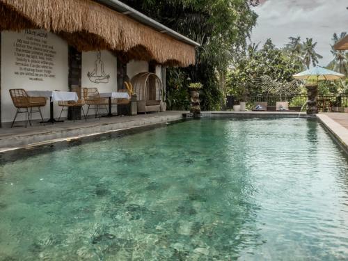 a swimming pool in front of a house at Tattva Ubud Retreat & Wellness in Ubud