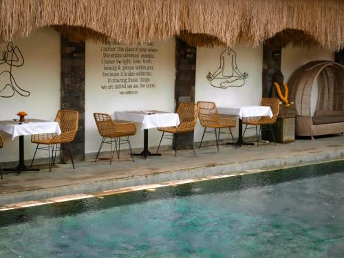 a restaurant with tables and chairs next to a swimming pool at Tattva Ubud Retreat & Wellness in Ubud