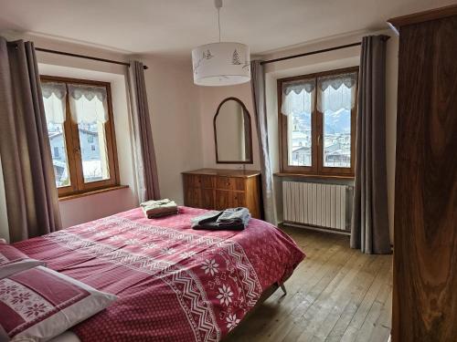 a bedroom with a bed with a red blanket and windows at THE YELLOW HOUSE in Bormio