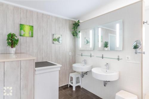 a bathroom with two sinks and two mirrors at Villa Punta Vista by Abahana Villas in Cumbre del Sol