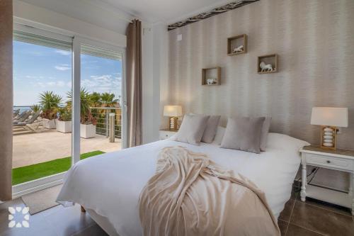 a bedroom with a white bed and a large window at Villa Punta Vista by Abahana Villas in Cumbre del Sol