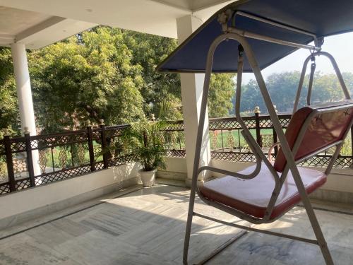 a chair on a balcony with an umbrella at Kashiyana Village Homestay in Shivāpur