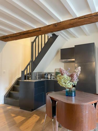 une cuisine avec une table avec un vase de fleurs dans l'établissement Les Chanoines Bayeux Cathédrale, à Bayeux