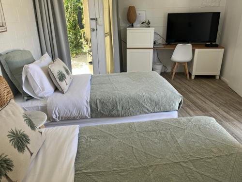 two beds in a room with a desk and a television at Peninsula Beach Motel in Rosebud