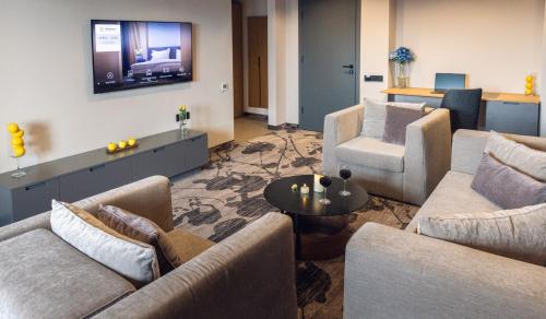 a living room with couches and a television on the wall at Kamengrad Hotel & SPA in Panagyurishte