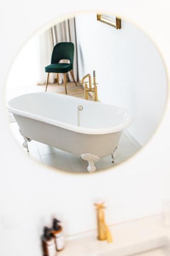 a mirror with a white bath tub and a chair at Boutiquehotel Zum Goldenen Hirschen in Gmunden