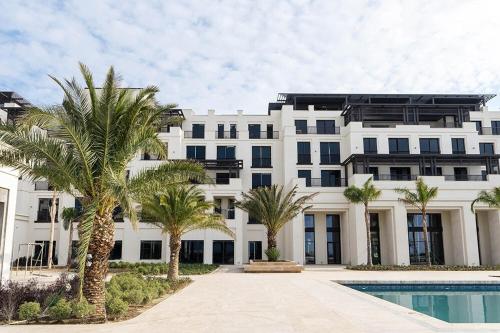 a large white building with palm trees and a swimming pool at Luxury Seaside Stay - SeaBreeze The Grand in Nardaran