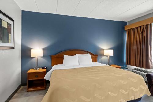 a bedroom with a large bed with a blue wall at Quality Inn & Suites CVG Airport in Erlanger