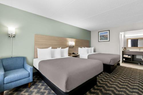 a hotel room with two beds and a blue chair at Quality Inn Nashville - Opryland Area in Nashville