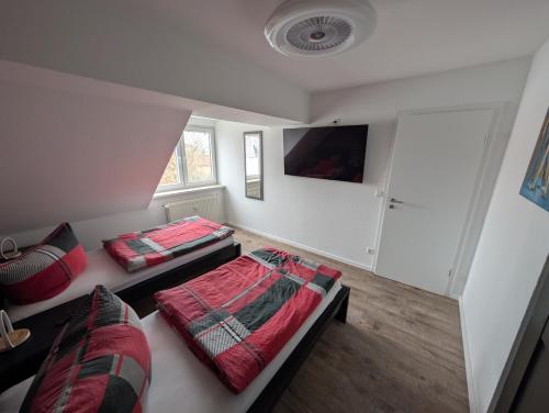 a bedroom with two beds and a tv on the wall at Richter Apartments Finsterwalde mit Klimaanlage in Finsterwalde