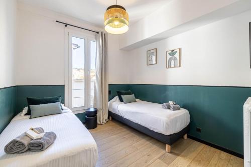 une chambre avec deux lits et une fenêtre dans l'établissement 29 ANDRE - Luxurious apartment 20m from beaches - Villa royale Croisette, à Cannes