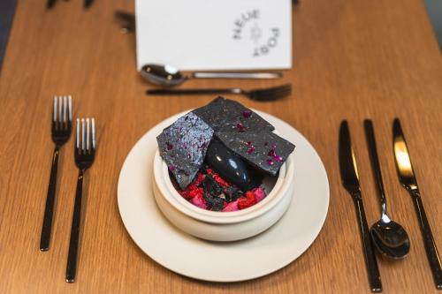 a white plate with a bowl of food on a table with silverware at Upside Down Town Hotel Neue Post in Zell am See
