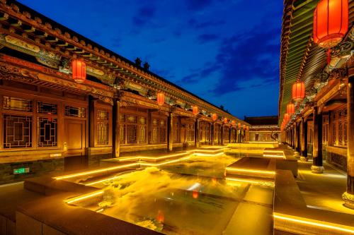 a building with a fountain in the middle of a street at Xinghuacun Hotel in Pingyao