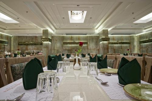 a dining room with a long table with green chairs at Golden Plaza in Ahmedabad