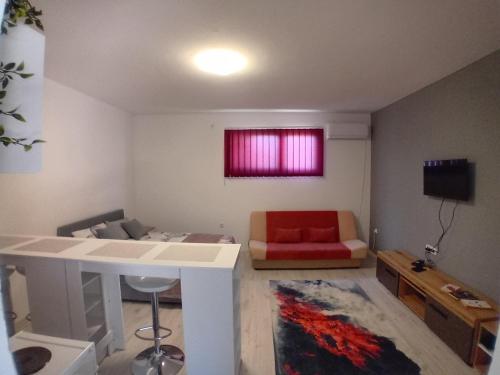 a living room with a couch and a red chair at AlejaPark Inđija in Železnicka Stanica Inđija Selo