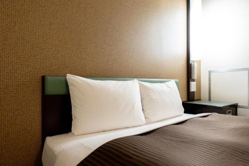 a bed with white pillows on top of it at Hotel Matsumoto Yorozuya in Matsumoto