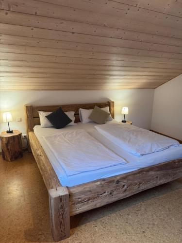 a large wooden bed in a room with two lamps at Ferienwohnung Heuboden in Reut