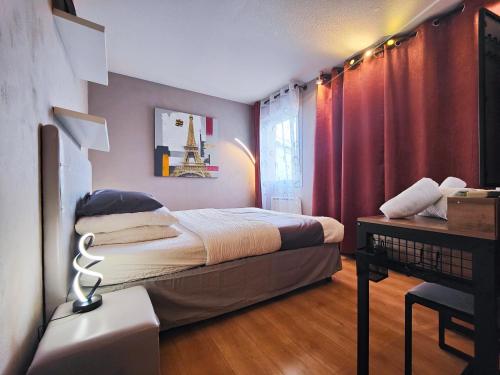 a bedroom with a bed and a table with a lamp at Cocoon'Inn Blagnac in Blagnac