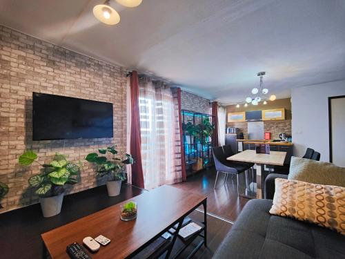 a living room with a couch and a tv on a brick wall at Cocoon'Inn Blagnac in Blagnac