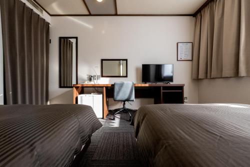 a hotel room with two beds and a desk with a computer at Hotel Matsumoto Yorozuya in Matsumoto