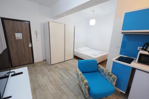 a room with a blue chair and a bed at Iassium Residence Iasi in Iaşi