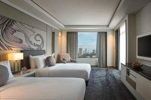a hotel room with two beds and a television at Amari Johor Bahru in Johor Bahru