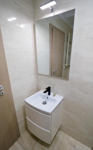 a white bathroom with a sink and a mirror at Iassium Residence Iasi in Iaşi