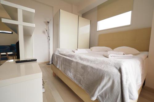 a bedroom with a bed with white sheets and a window at Iassium Residence Iasi in Iaşi