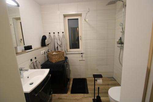 a white bathroom with a sink and a toilet at Apartment Grey am See mit Zugang in Zeuthen