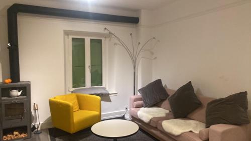 a living room with a couch and a yellow chair at Maison verte in Roche