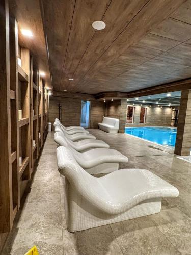 a row of white chairs in a room with a pool at Bóris House in Ognyanovo