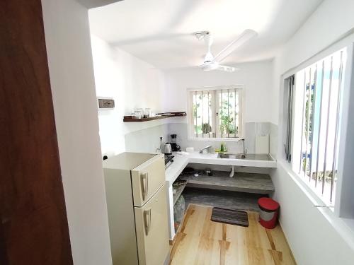 a white kitchen with a sink and a refrigerator at White Villa - Homestay in Tangalle