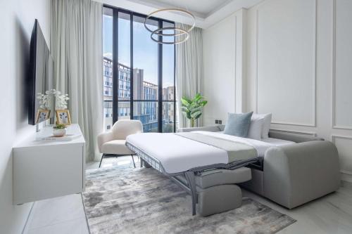 a white bedroom with a bed and a large window at Frank Porter - Samana Park Views in Dubai