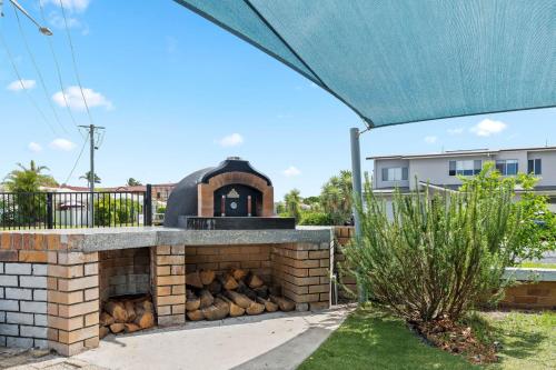 an outdoor pizza oven in a backyard with a blue awning at Sea Breeze on Gibbon - Walk to the Beach and the Bowlo in Lennox Head