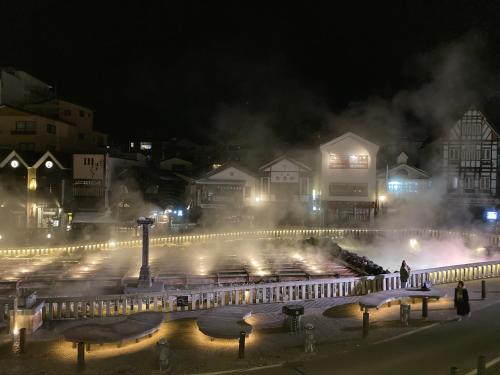 a city lit up at night with smoke and lights at Hotel Sakurai in Kusatsu