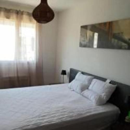 une chambre avec un lit avec des draps blancs et une fenêtre dans l'établissement Maison avec piscine privée aux portes des Cévennes, à Saint-Christol-lès-Alès