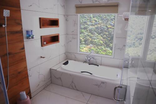 a bathroom with a bath tub and a window at The TeaTree Munnar in Suryanelli