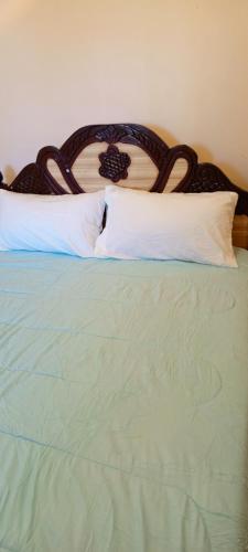 a green bed with a wooden headboard and white pillows at EsMash Homes Air,bnb Lanet Nakuru in Nakuru