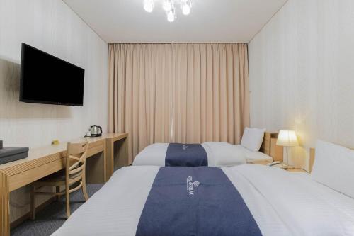 a hotel room with two beds and a desk and a television at Incheon Aiport Airrelax hotel in Incheon