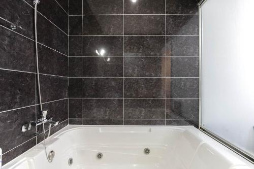 a bath tub in a bathroom with black tiles at Incheon Aiport Airrelax hotel in Incheon
