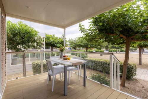 a white table and chairs on a deck with a tree at ReBi Village in Imperia