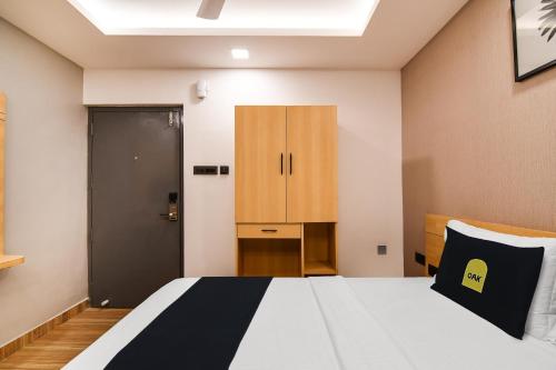 a bedroom with a bed and a cabinet at Super Townhouse OAK Sayhallo Ecstasy in Bhubaneshwar