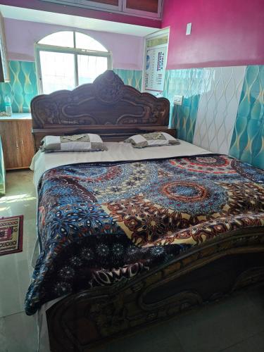 a large bed in a room with a colorful quilt at Texoya Zostellers Homestay in Bihār Sharīf