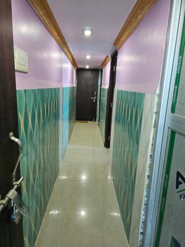 a corridor of a bathroom with green and blue tiles at Texoya Zostellers Homestay in Bihār Sharīf