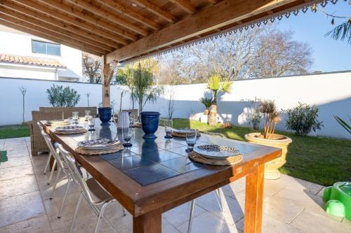 - une table en bois sur une terrasse avec des chaises dans l'arrière-cour dans l'établissement L'Espérance - Belle terrasse proche de la plage, à Gujan-Mestras