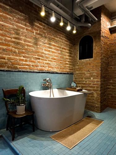 a large white bath tub in a room with a brick wall at Cataleya Estate Boutique Bed & Breakfast in Bangkok