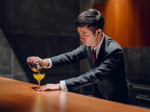 a man in a suit pouring a glass of wine at FIVE SPRING RESORT THE SHIRAHAMA in Shirahama