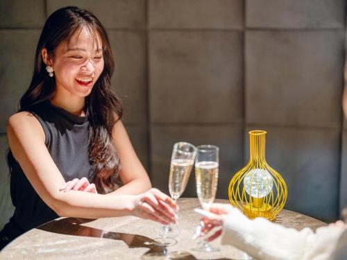 a woman sitting at a table with champagne glasses at FIVE SPRING RESORT THE SHIRAHAMA in Shirahama